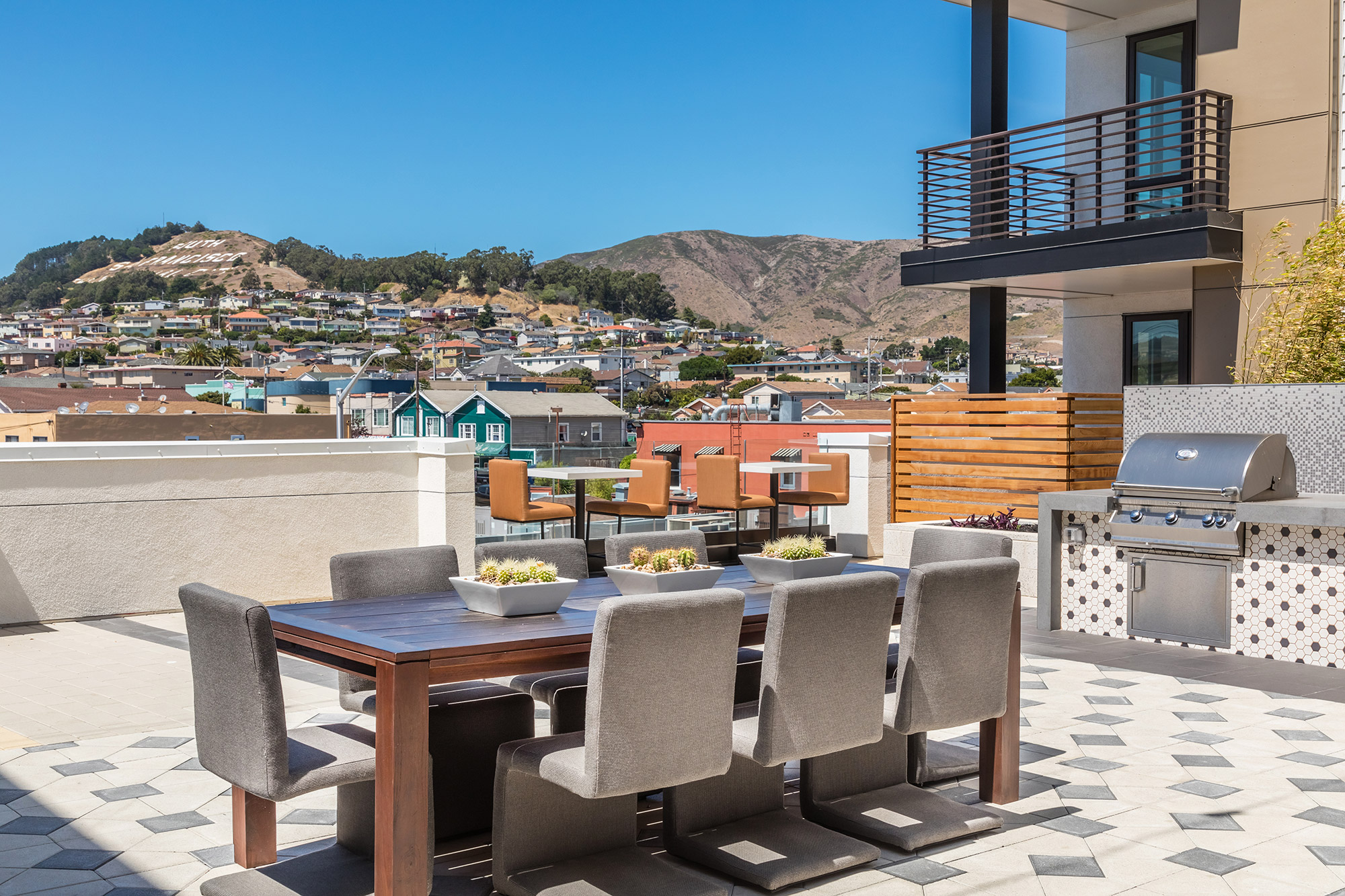 Rooftop area with table seating, community grill, bistro style seats and town views.