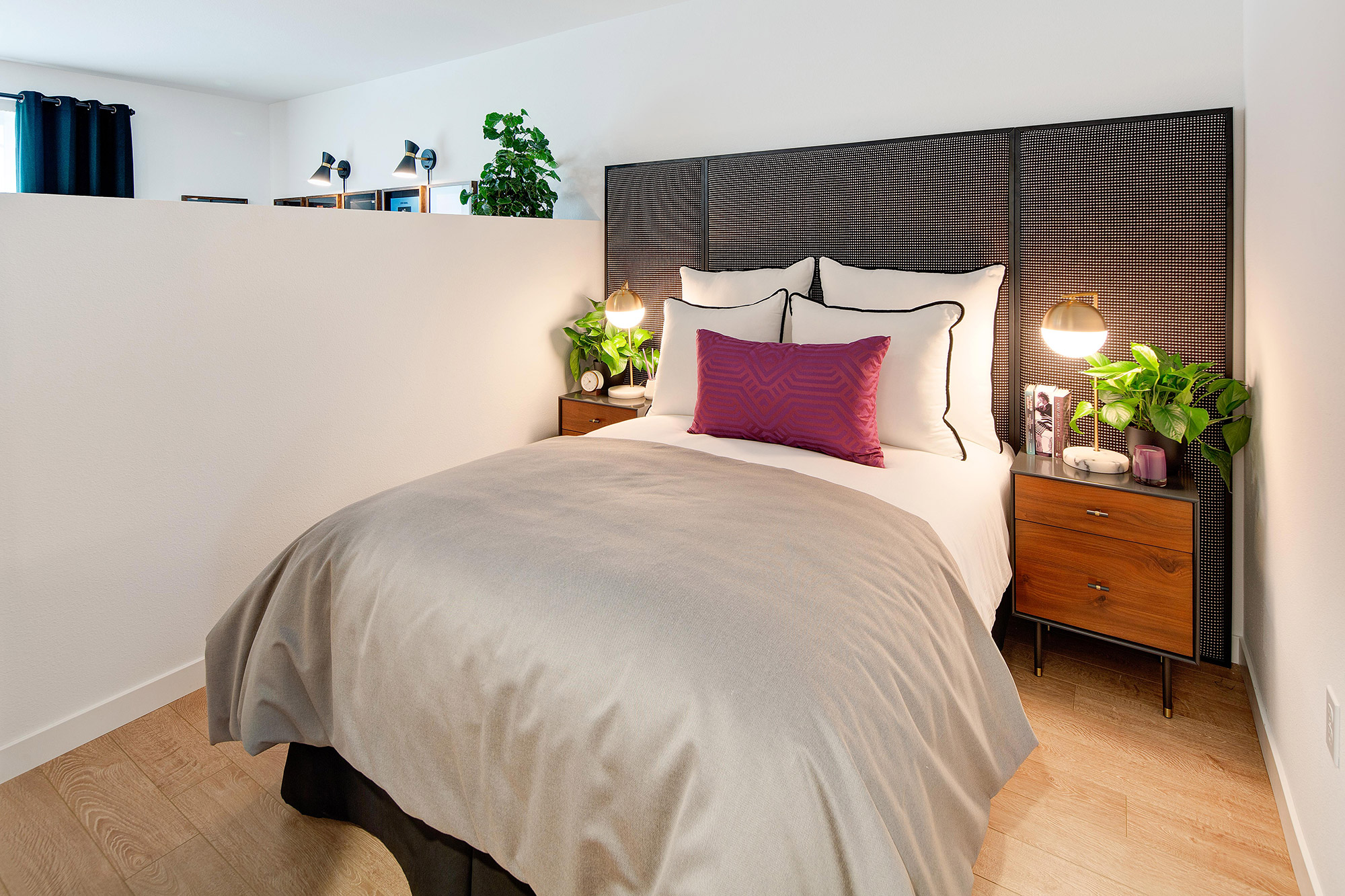 Bedroom with wood-style flooring, queen-sized bed, nightstands, and a privacy wall.