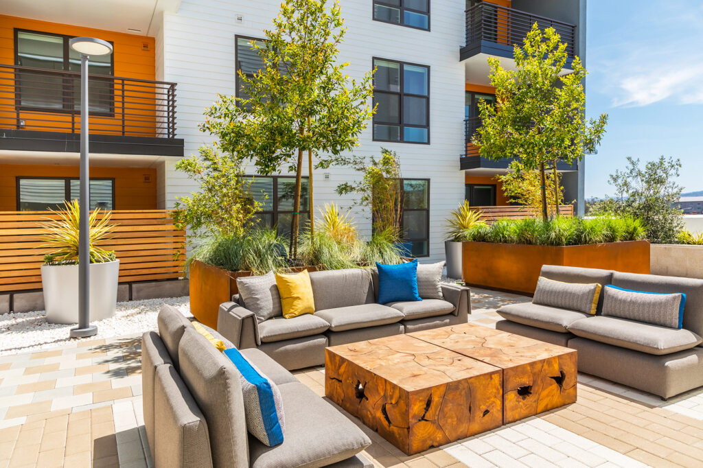 Patio area with plush couch seating and lush landscaping.