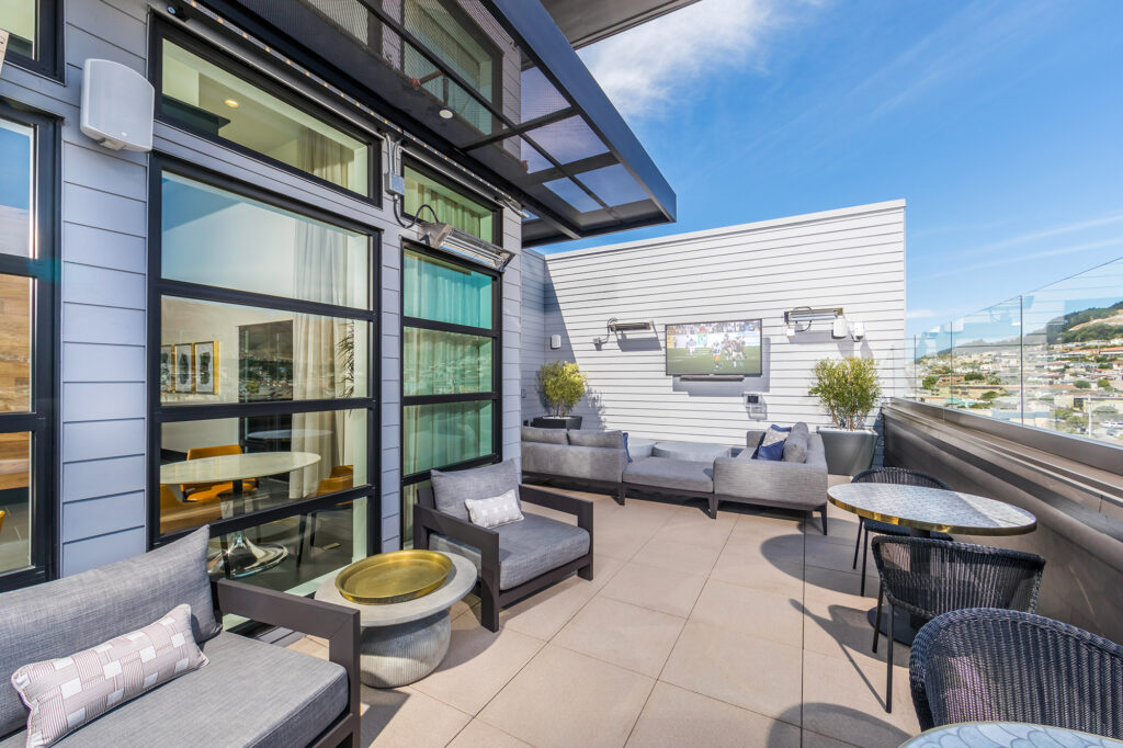 Terrace with table seating, couches, and flat-screen TV and town views