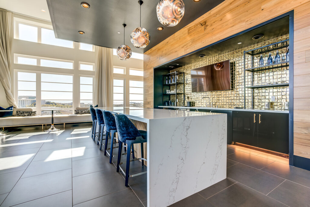 Clubhouse kitchen area with family-style seating, bistro-style seating, large wall-mounted TV and large windows overlooking the town.
