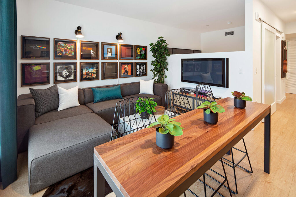 Living room with music frames, flat-screen TV, sectional couch and bar-style seating at kitchen island.