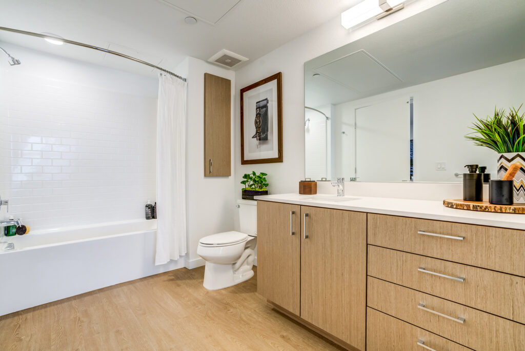Bathroom with wood-style floors, large single sink vanity with counter space, and tub/shower combo.