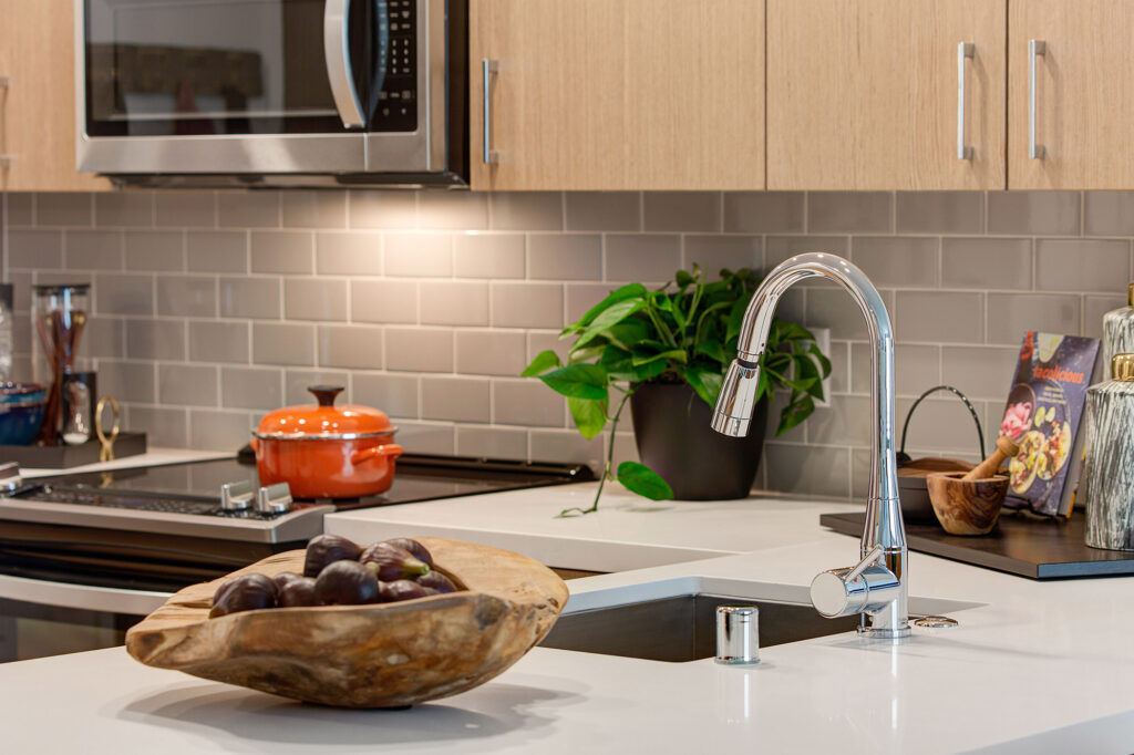 Kitchen detail of quartz counters and single basin stainless steel sink.