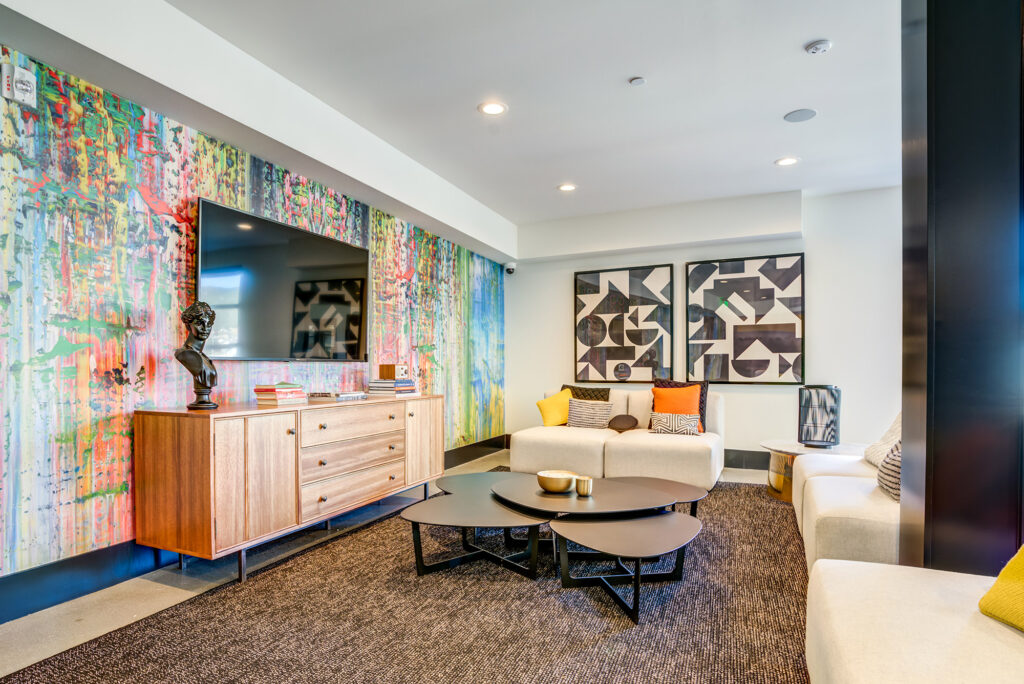 Seating area with colorful accent wall, wall-mounted TV, and plush seating.