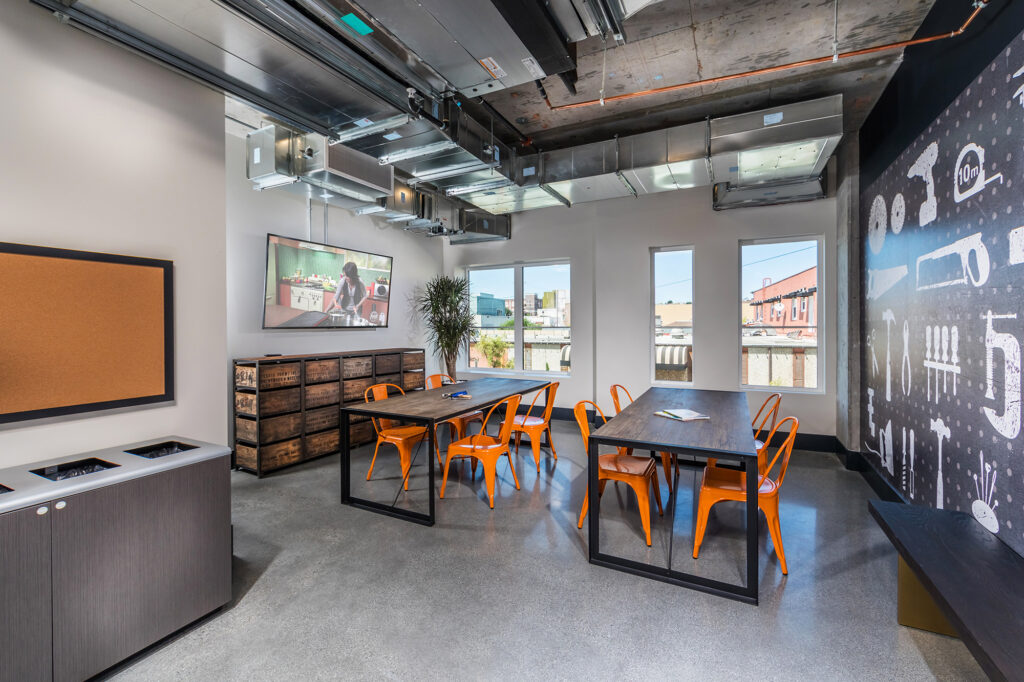 Seating area with two tables, wall-mounted TV, and accent wall.