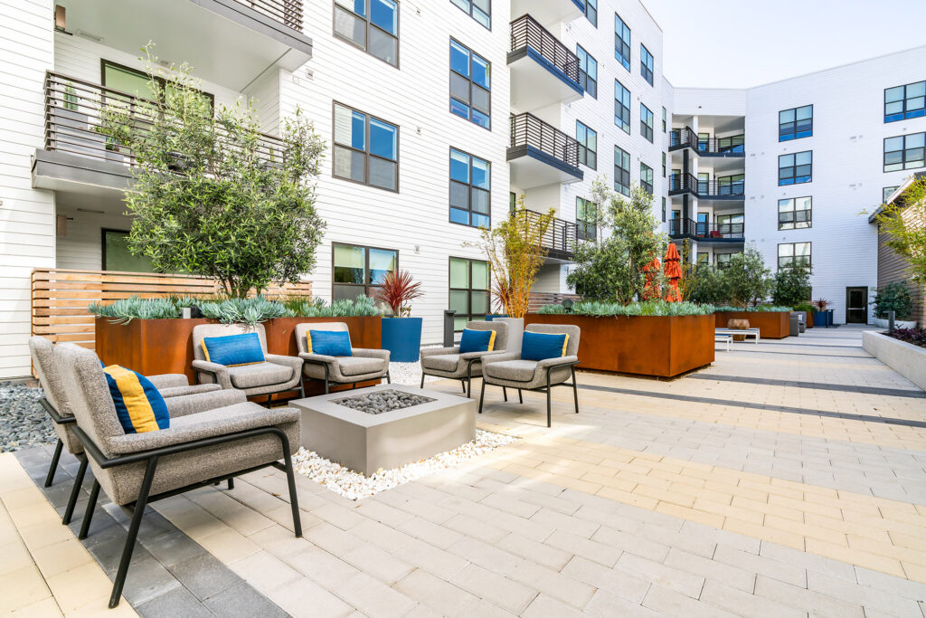 Patio area with seating around a fire pit and lush landscaping.
