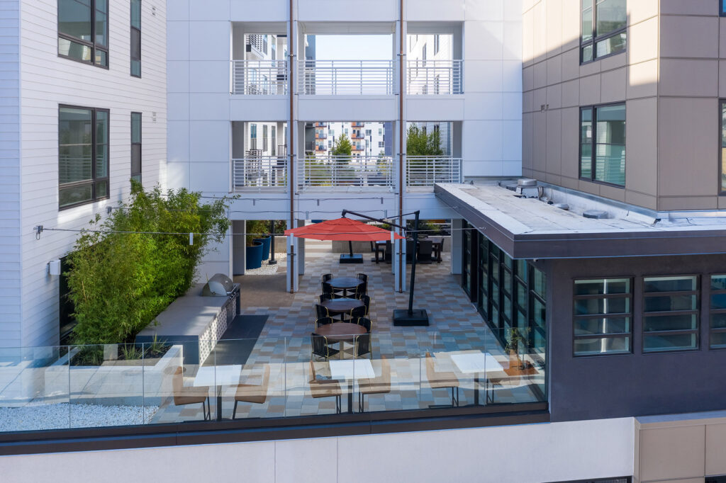 Rooftop area with table seating, community grill, bistro style seats and patio umbrella.
