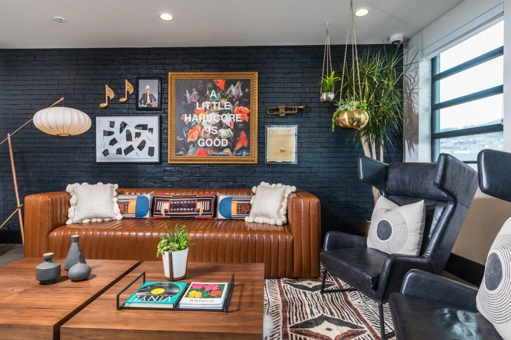 Lobby area with black brick wall, modern furniture, windows and music inspired art.
